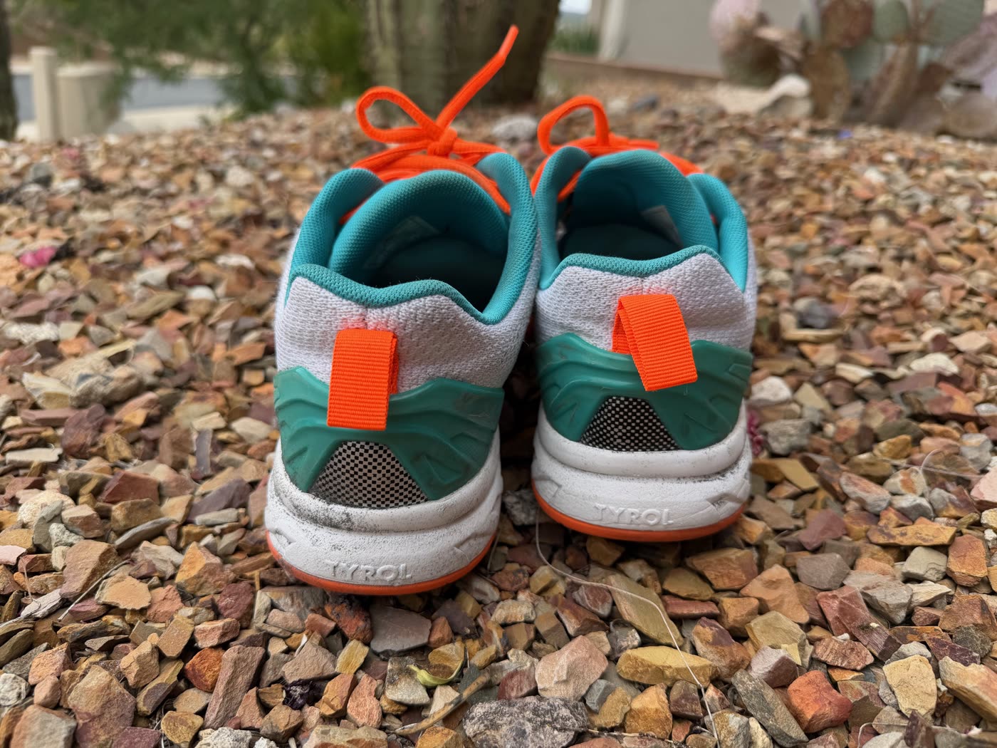 Heel view of the Tyrol Velocity V pickleball shoes showing the teal padded ankle collar, orange heel pull tab, and structured rear midsole with TYROL branding