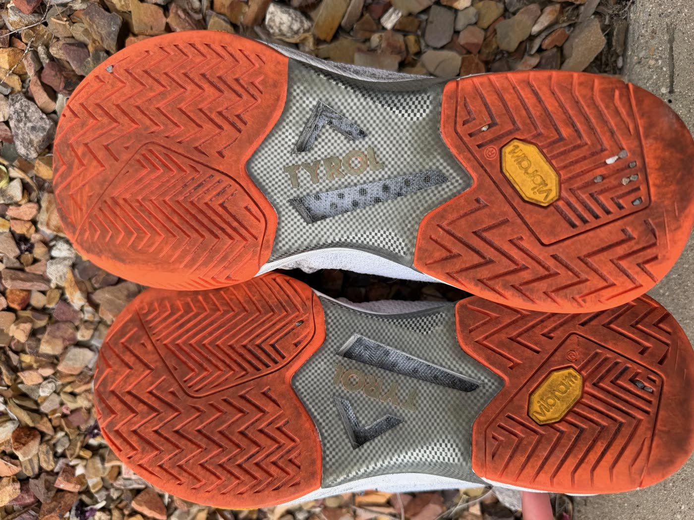Bottom view of both Tyrol Velocity V shoes after ~20 months of pickleball play, showing the orange Vibram herringbone outsole with limited wear under the big toe push-off area and tread pattern still well-defined