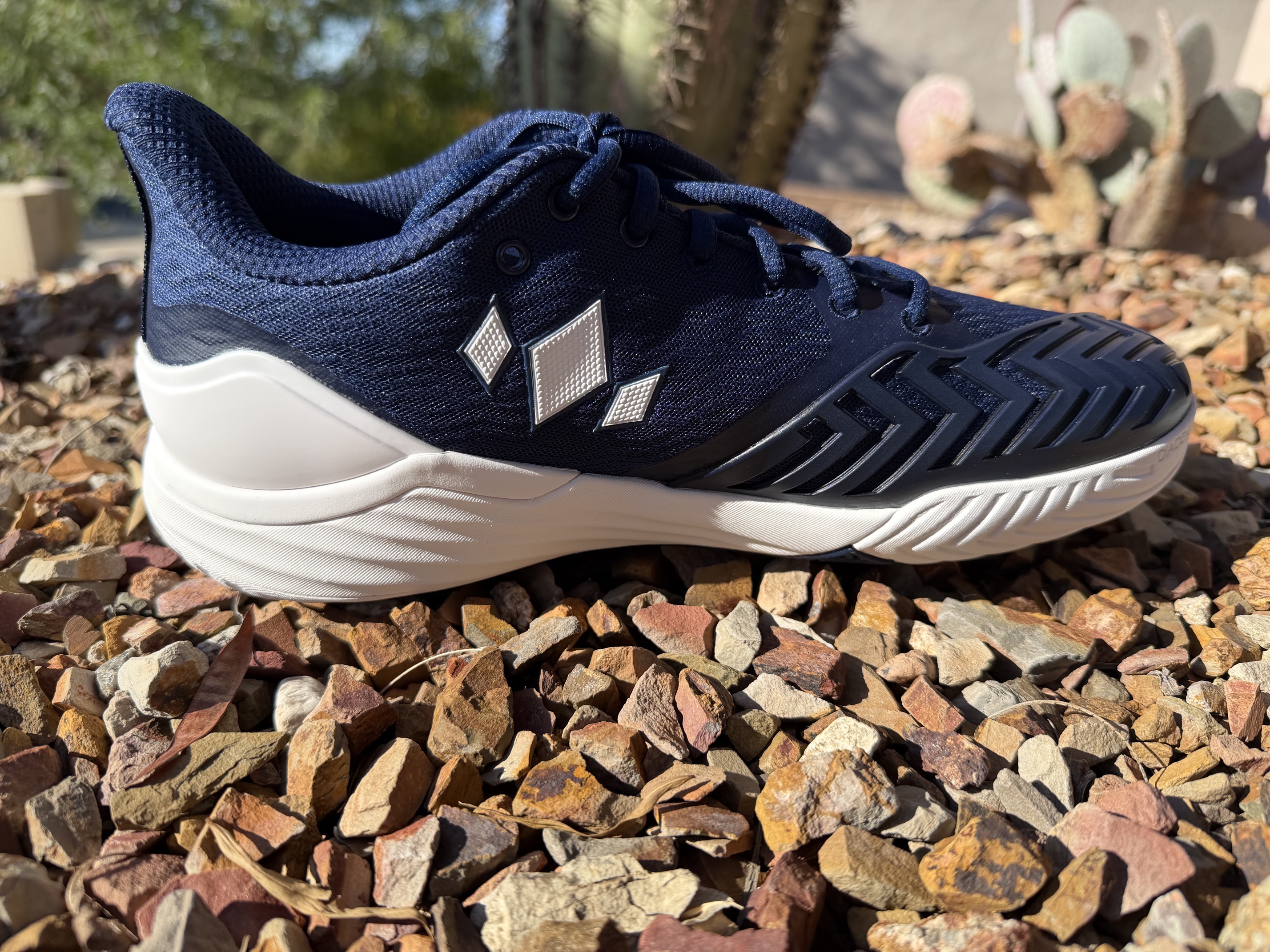 Medial side view of one Diadem Court Burst shoe in navy and white, showing drag-toe protection rubber wrapping the toe and the lighter overlay pattern on the medial side compared to the lateral Rebound X system.